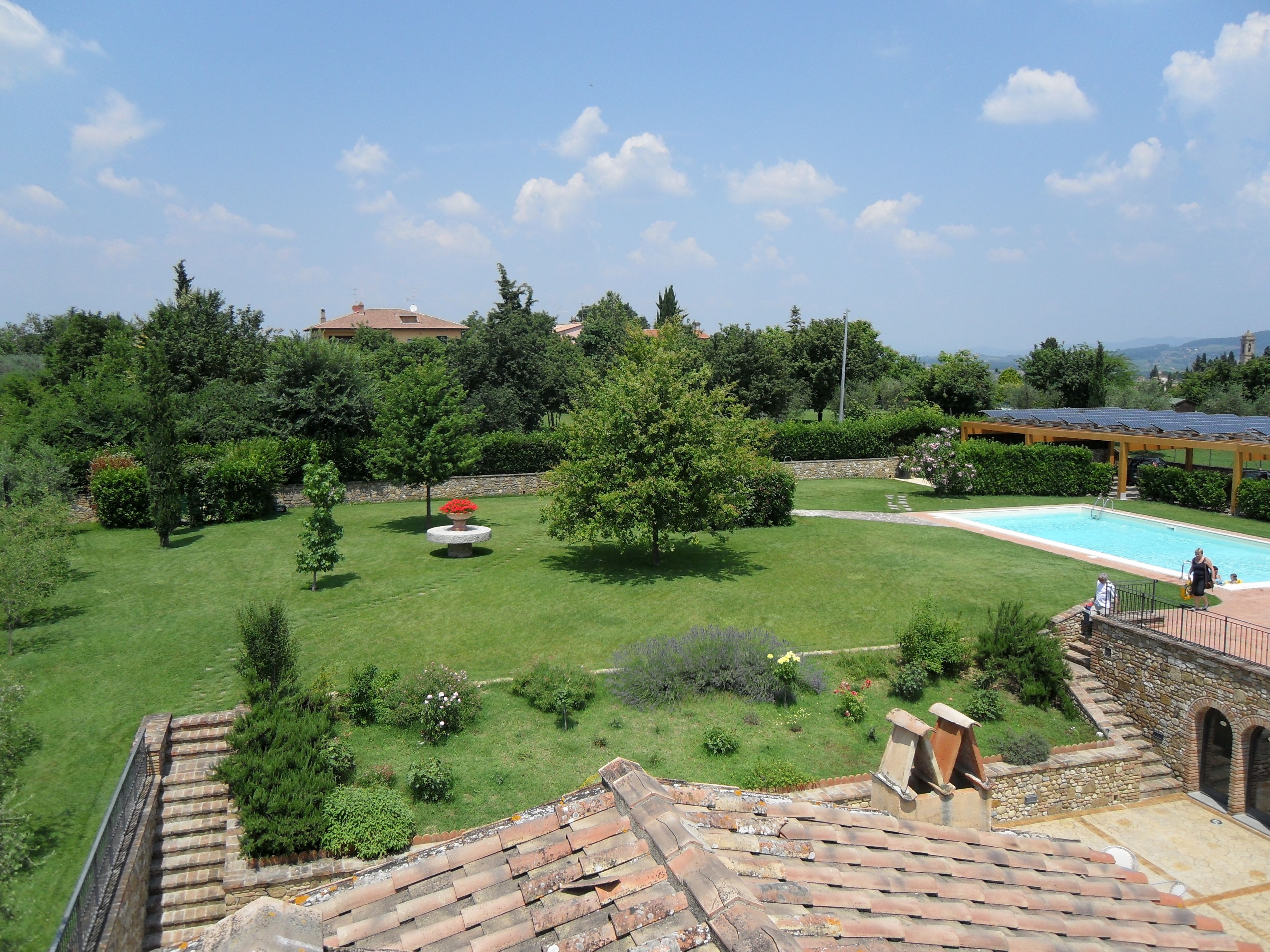 Una terrazza sul tetto con piscina, verde lussureggiante e un muro in pietra.