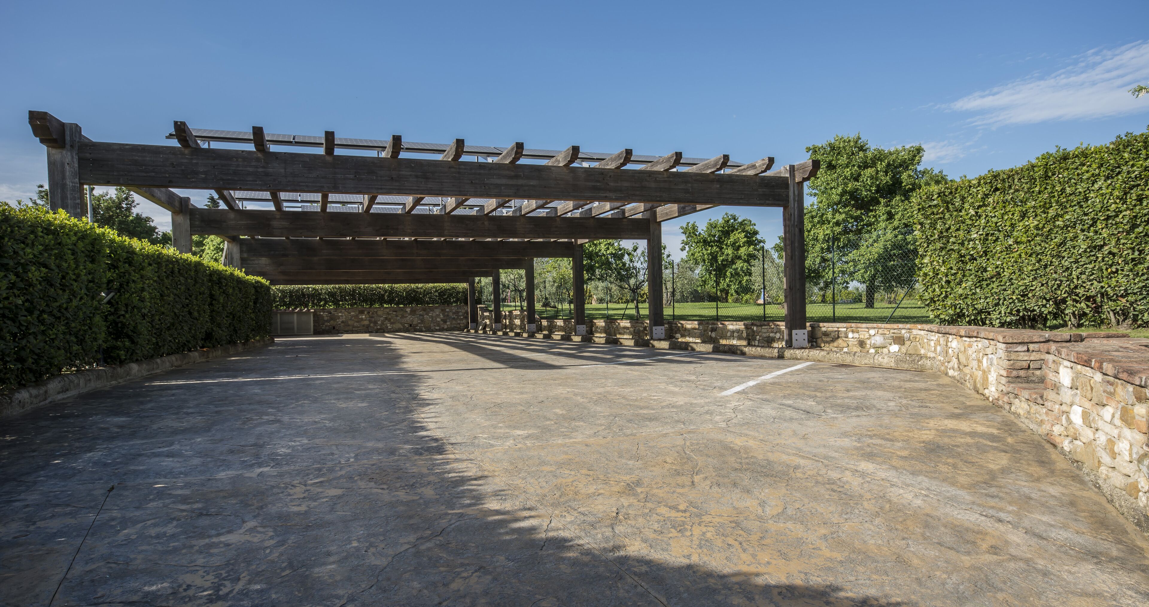A covered outdoor area with a stone wall and a wooden pergola structure.