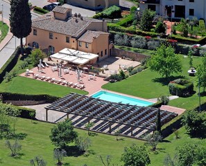 Vue aérienne d’un hôtel doté d’une piscine, d’un espace extérieur aménagé pour se détendre et de jardins bien entretenus.