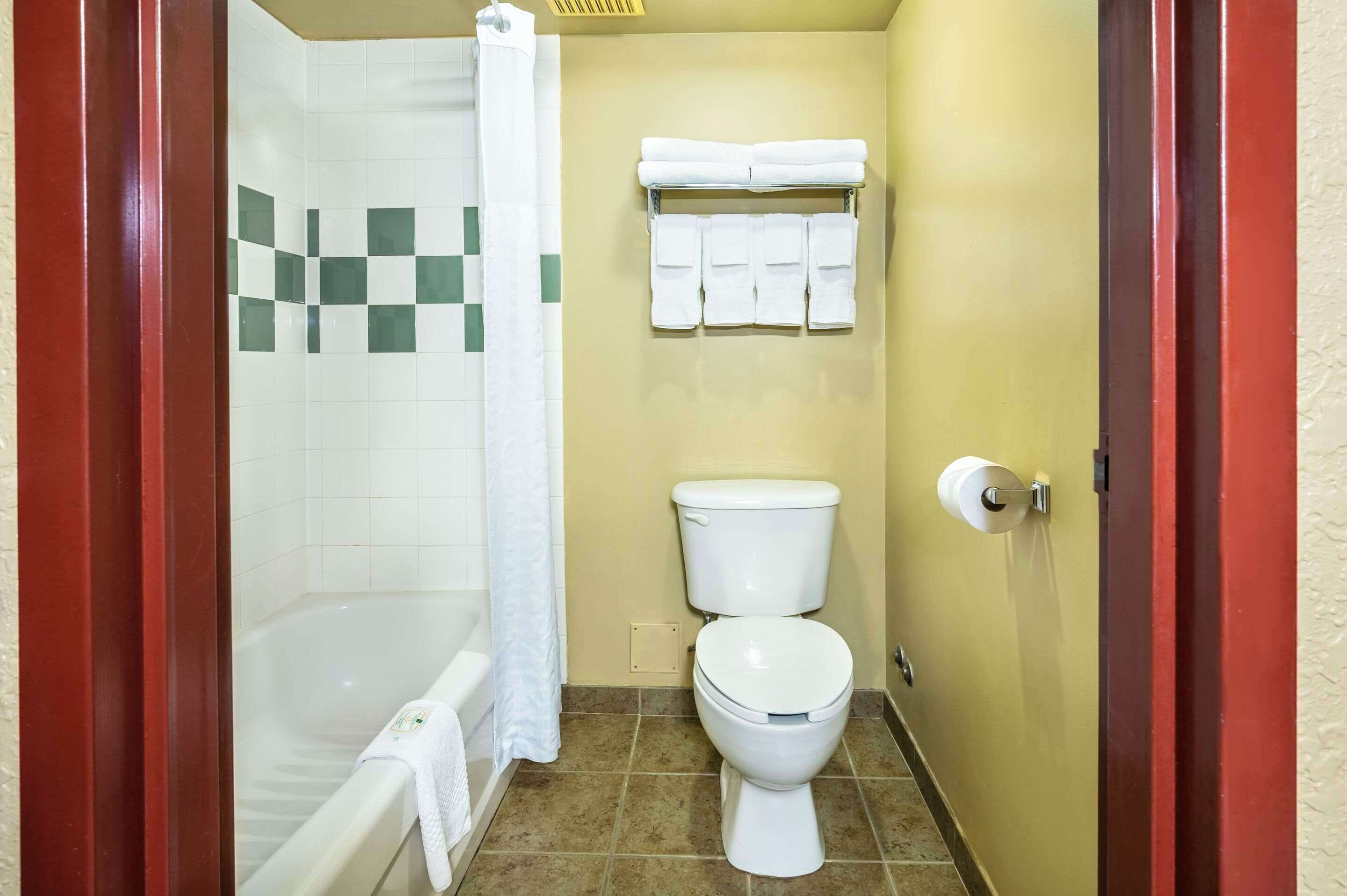 Un baño con bañera, inodoro y un perchero con varias toallas.
