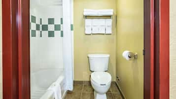 Un baño con bañera, inodoro y un perchero con varias toallas.