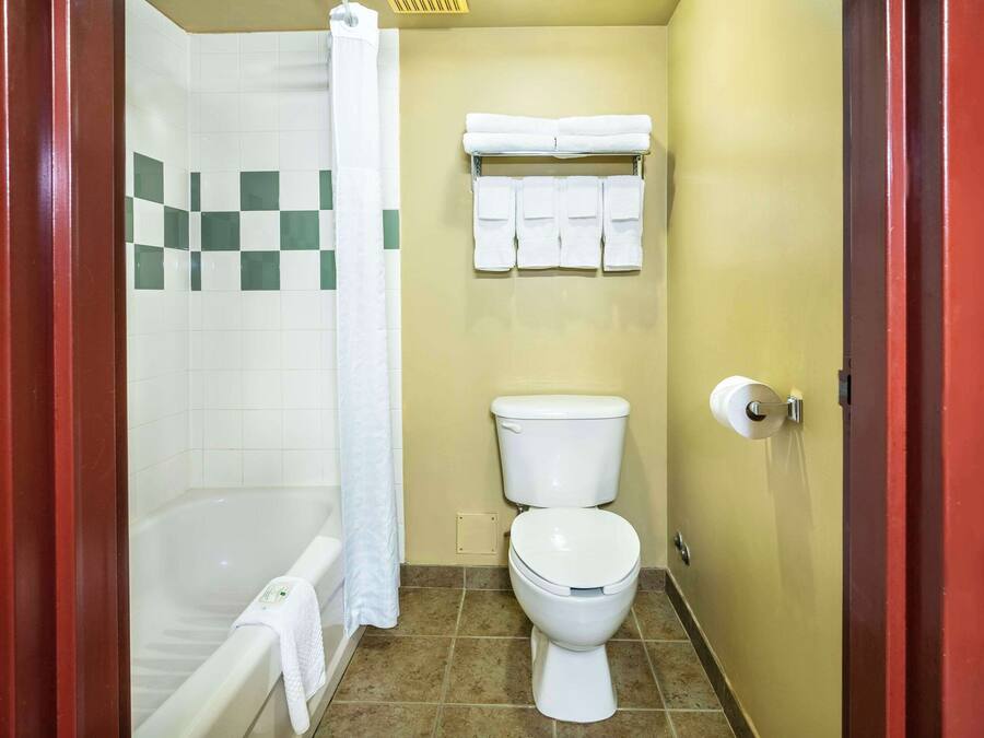 Un baño con bañera, inodoro y un perchero con varias toallas.