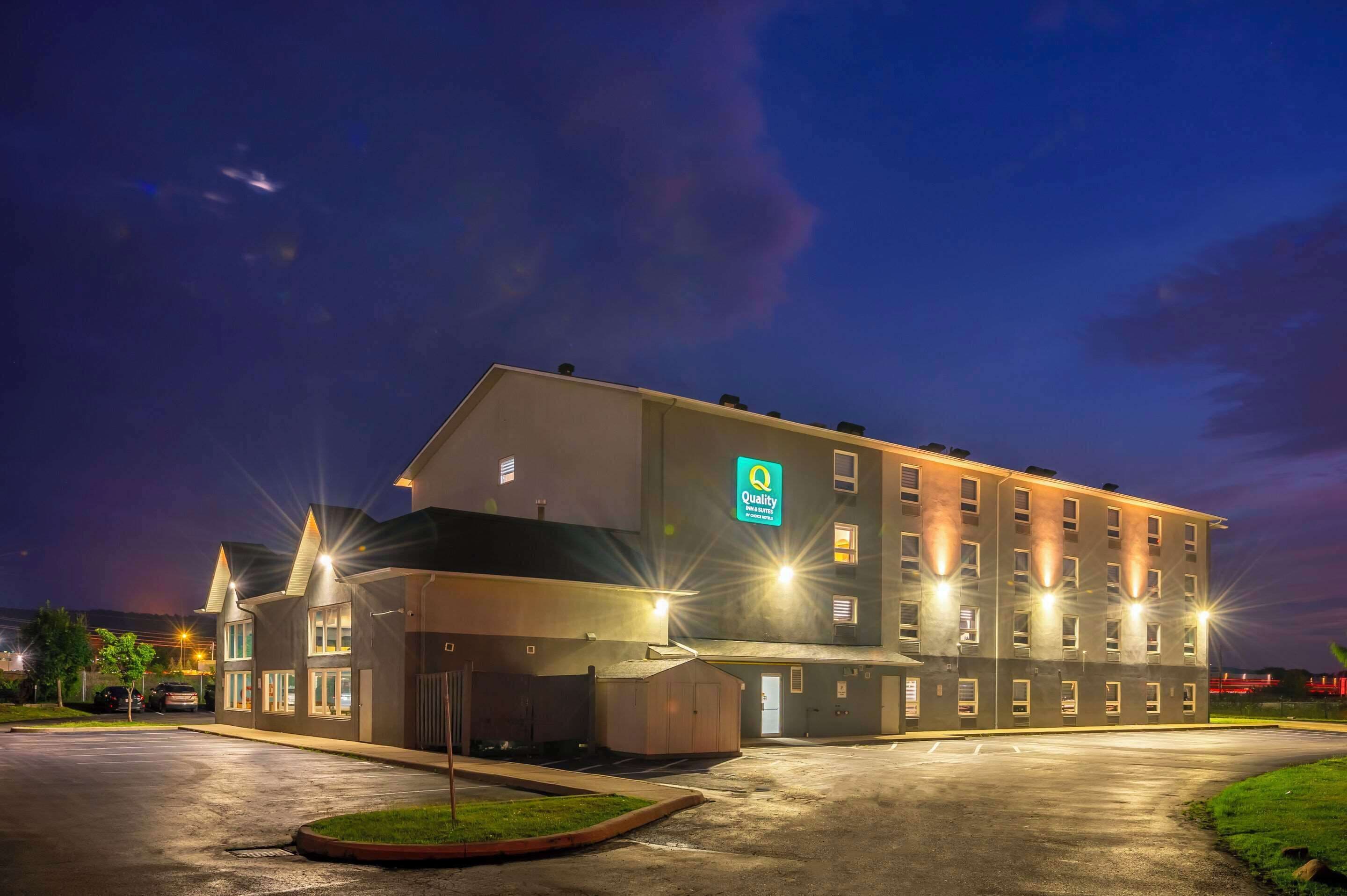 Hotel de diversos pisos amb un senyal ben visible de 'Quality', un aparcament i façana ben il·luminada.