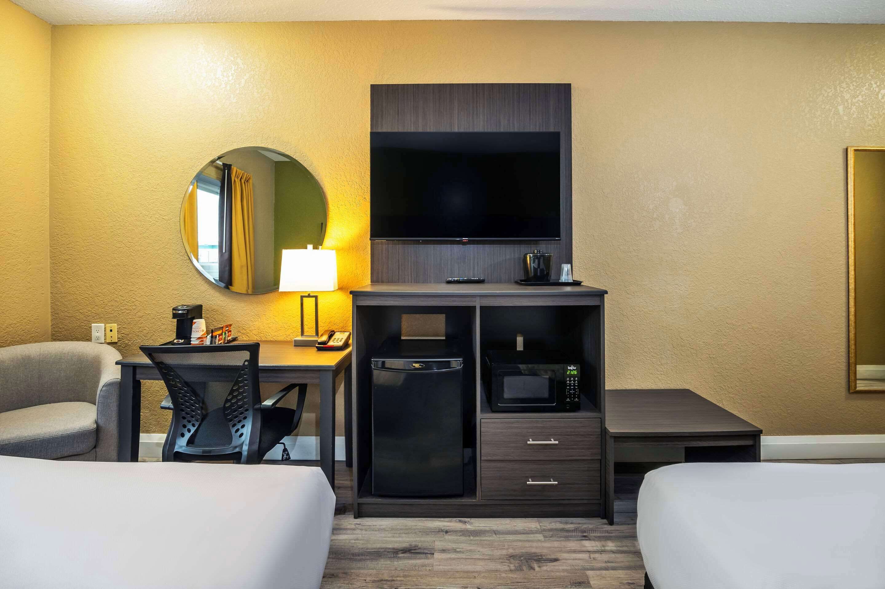 Habitación de hotel con cama, escritorio con computadora, televisión, microondas y cafetera.