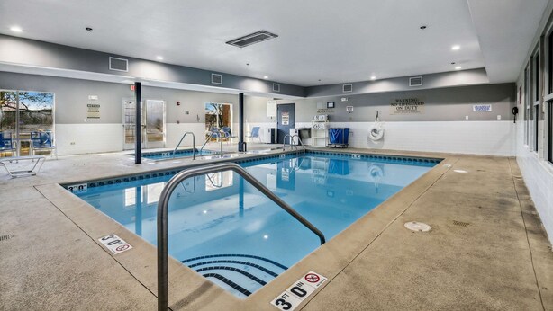 An indoor swimming pool with a clear water surface, a metal ladder, and a no diving sign.