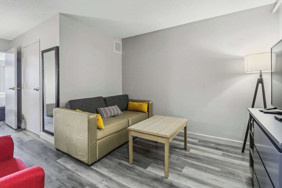 A modern living room with a sofa, a small table, and a lamp.