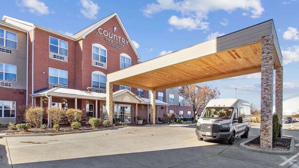 A Country Inn & Suites with a covered parking area and a van parked inside.