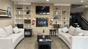 A living room with two sofas, a fireplace, a TV, and a bookshelf.