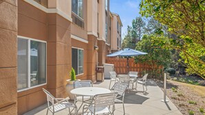 An outdoor patio with a round table and chairs, a trash can, and a wooden fence. - Fairfield Inn & Suites by Marriott Columbus (Columbus)