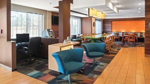 A hotel lobby with a reception desk, computer, seating area, and a large screen. - Fairfield Inn & Suites by Marriott Columbus (Columbus)