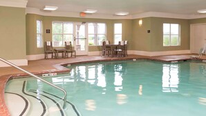 An indoor swimming pool with clear water, a pool ladder, and a seating area with chairs and tables. - Homewood Suites by Hilton Indianapolis-Airport/Plainfield (Plainfield)