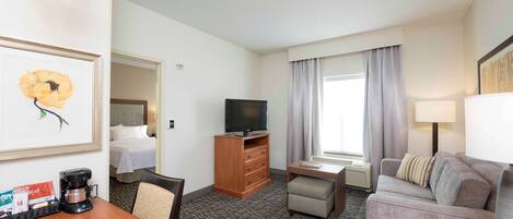 A hotel room with a bed, a desk, a television, a sofa, and a coffee maker.