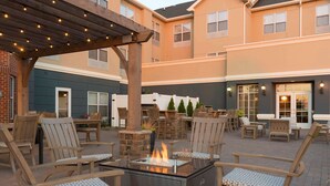 An outdoor patio area with a fire feature, wooden chairs, and a pergola. - Homewood Suites by Hilton Indianapolis-Airport/Plainfield (Plainfield)
