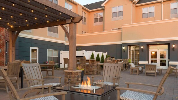 An outdoor patio area with a fire feature, wooden chairs, and a pergola. - Homewood Suites by Hilton Indianapolis-Airport/Plainfield (Plainfield)