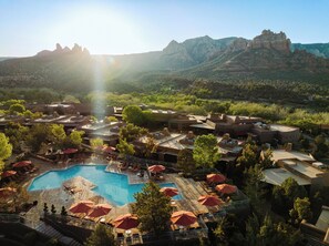 A resort with a swimming pool surrounded by outdoor seating and umbrellas, set against a backdrop of mountains and clear skies. - Hyatt Vacation Club at Pinon Pointe, Sedona (Sedona)