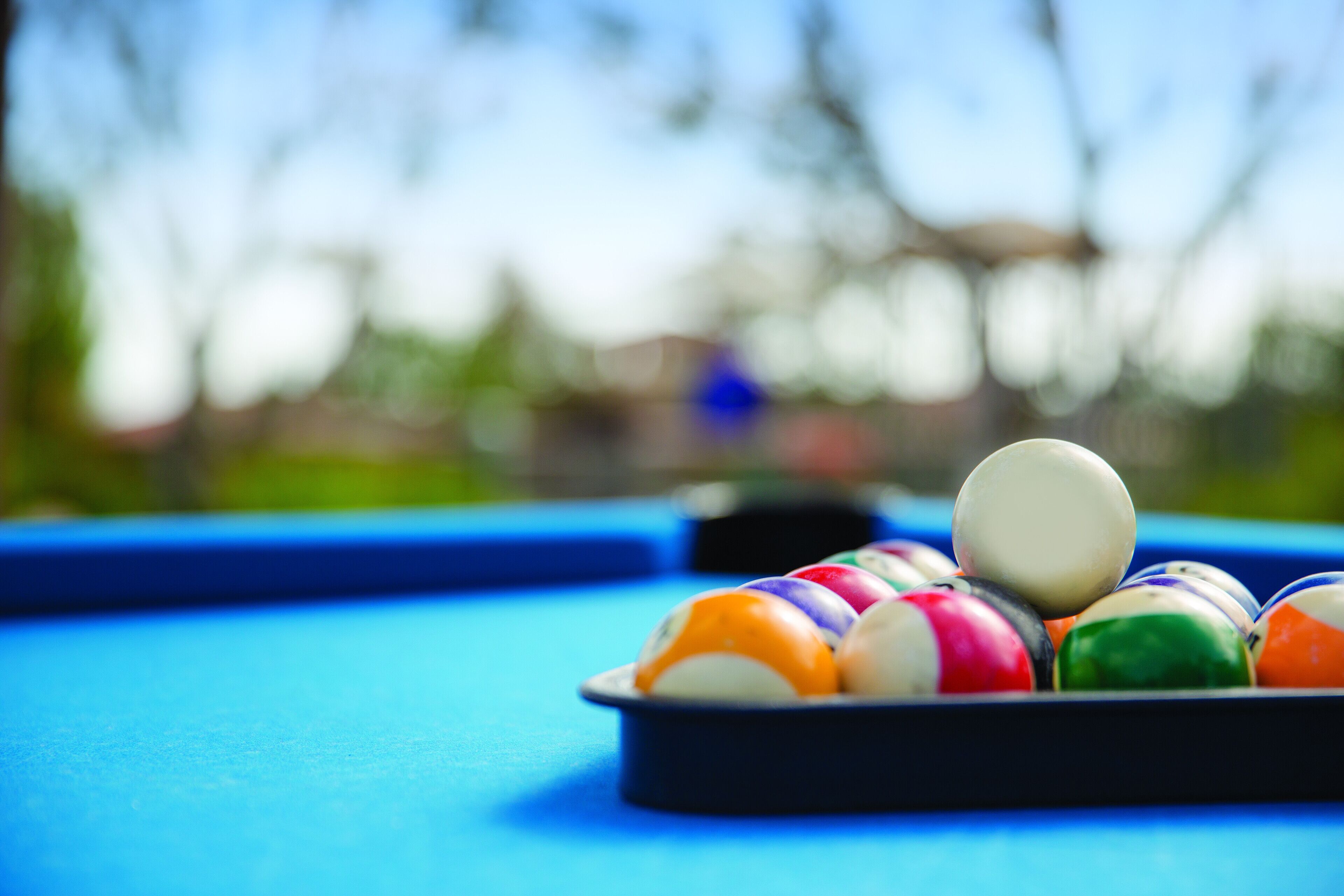 A pool table with a blue surface and colorful balls arranged in a rack.