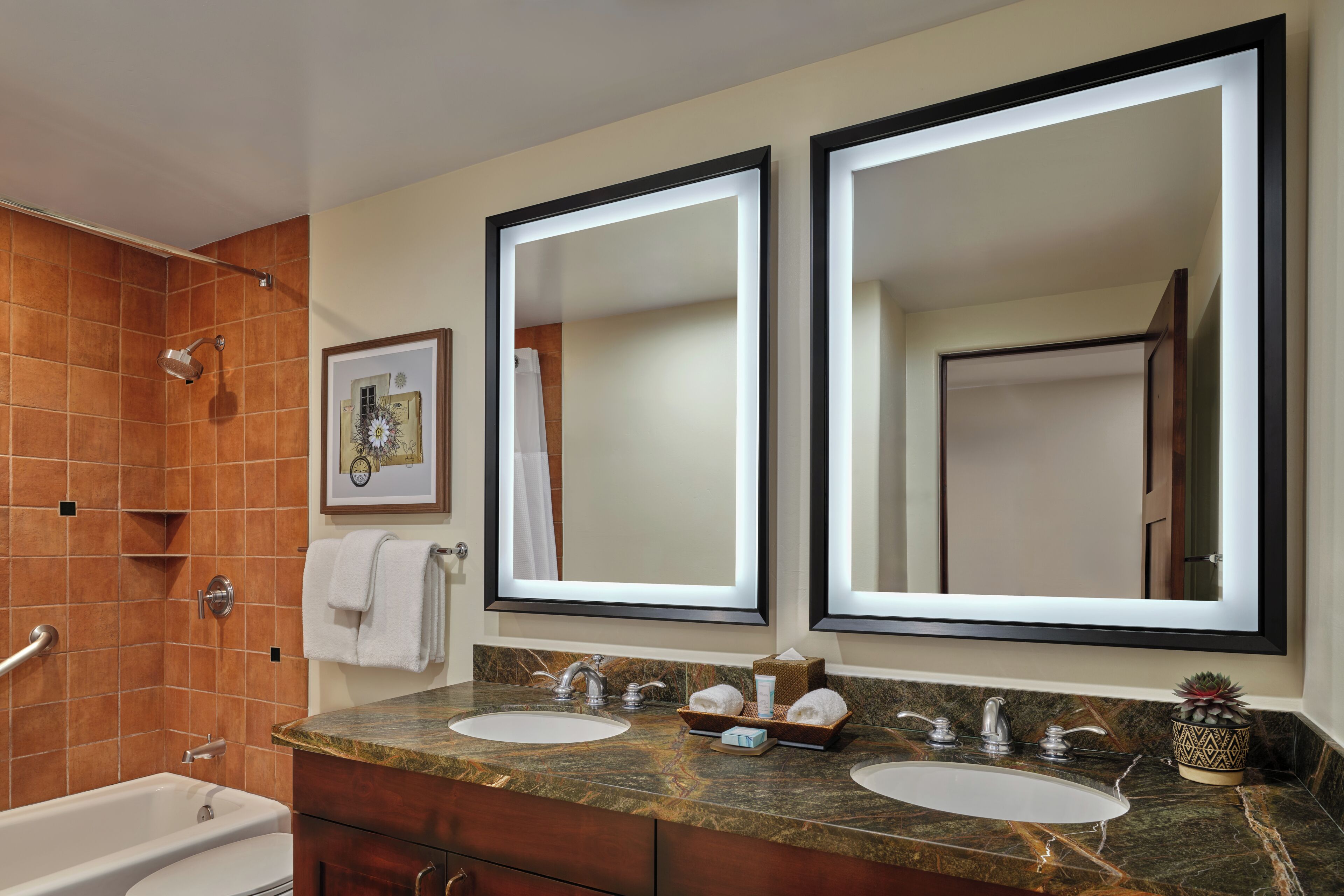 A bathroom with two sinks, a bathtub, a shower, and two large mirrors.