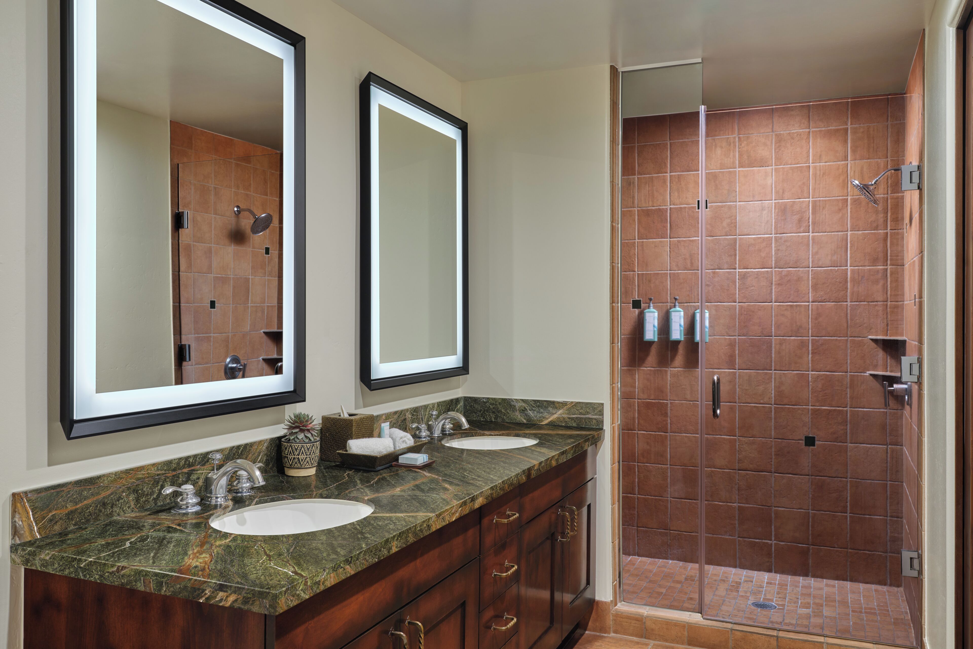 Une salle de bain avec deux lavabos, un miroir et un espace douche.