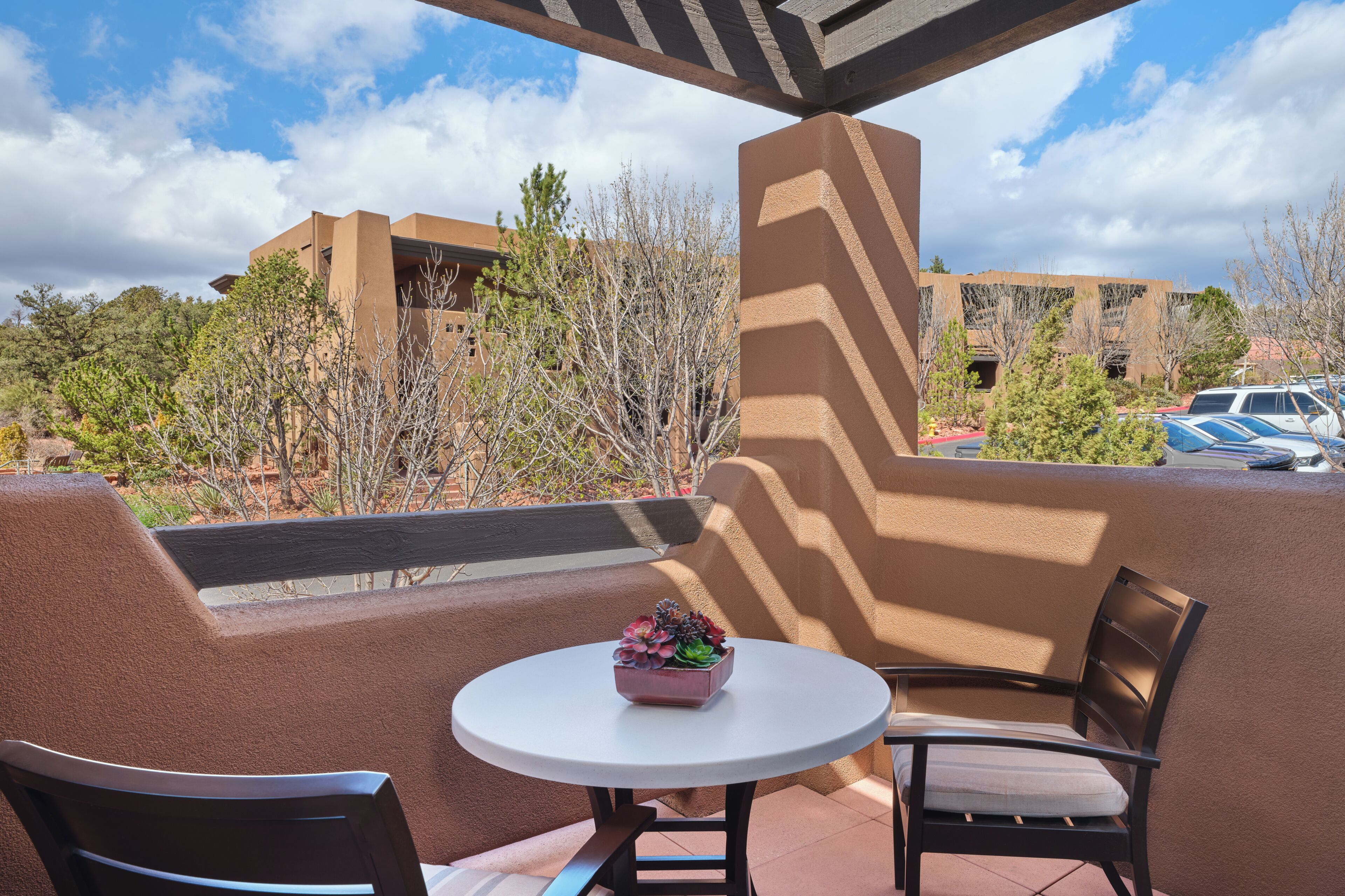 Un balcon avec une table ronde, deux chaises et une petite plante en pot.
