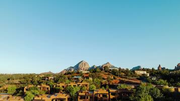 A residential area with modern houses, a prominent mountain in the background, and a clear blue sky.