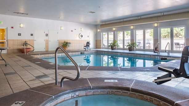 Une piscine intérieure avec un poste de surveillance pour le sauveteur, un jacuzzi et une chaise longue.