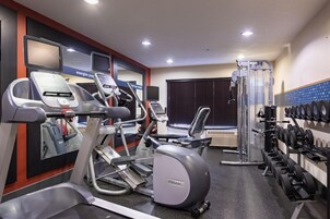 Un gimnasio con cintas de correr, elípticas, un banco de pesas y una máquina de poleas.