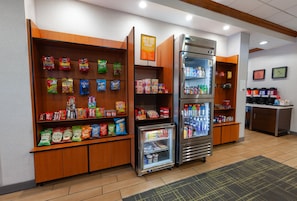 Estación autoservicio de aperitivos y bebidas con opciones refrigeradas y sin refrigerar, incluyendo papas fritas, bocadillos y refrescos.