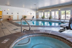 Piscina interna com hidromassagem, piso revestido e plantas em vasos.