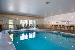 An indoor swimming pool with clear water, a lifeguard station, and seating areas.