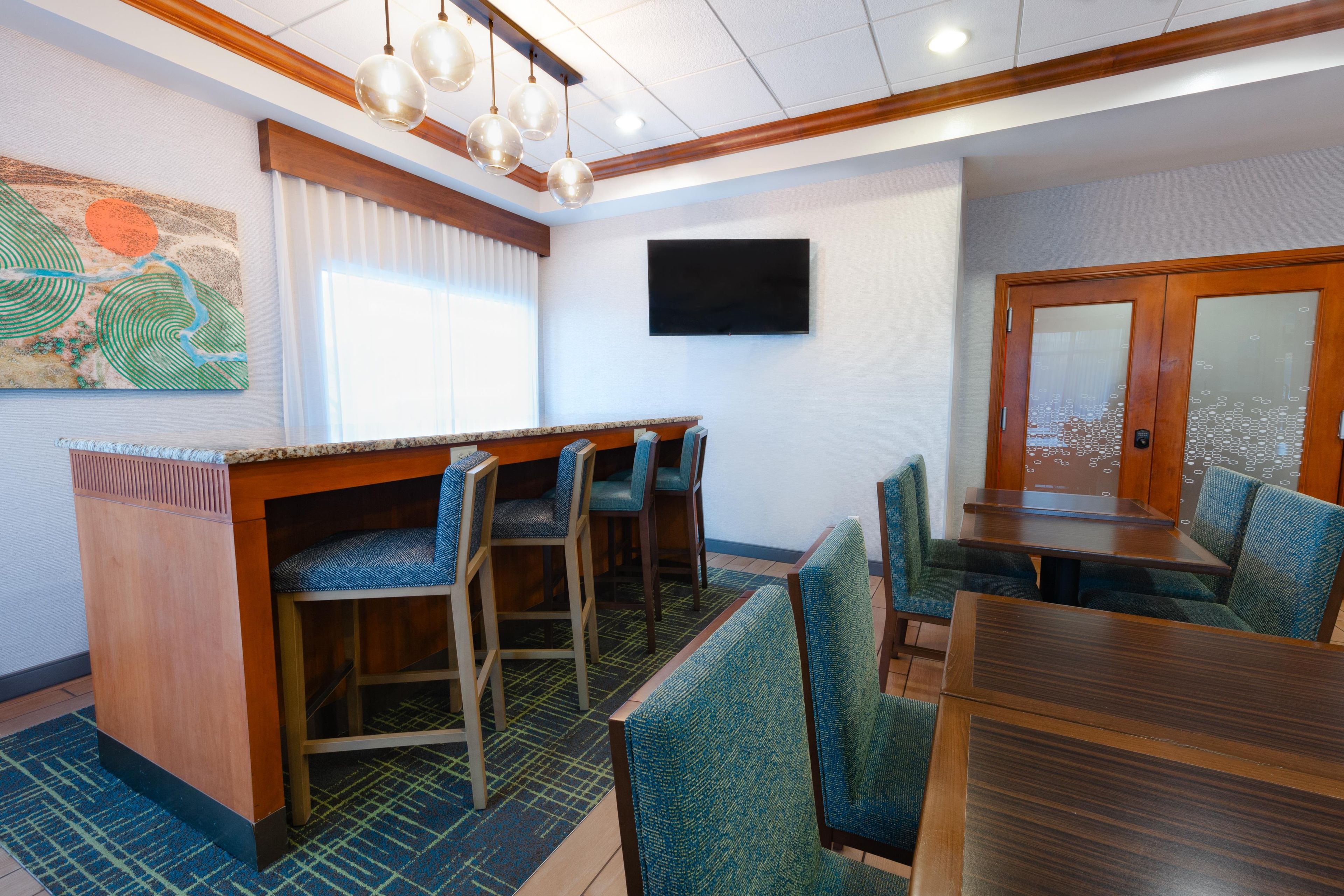A hotel dining area with a bar, seating, and a flat-screen TV.