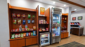 Un espace de libre-service proposant des collations et des boissons, avec des options réfrigérées et non réfrigérées, notamment des chips, des en-cas et des boissons en bouteille.
