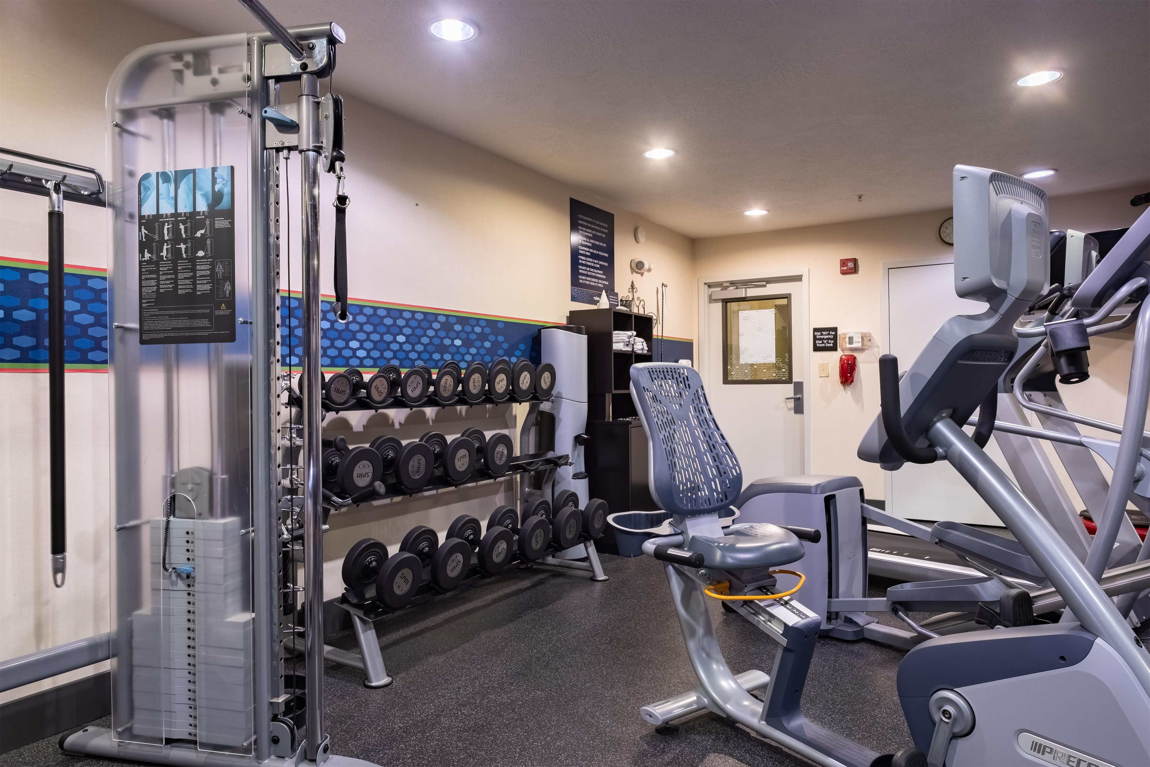 Un gimnasio con equipo de levantamiento de pesas, mancuernas y máquinas de cardio.