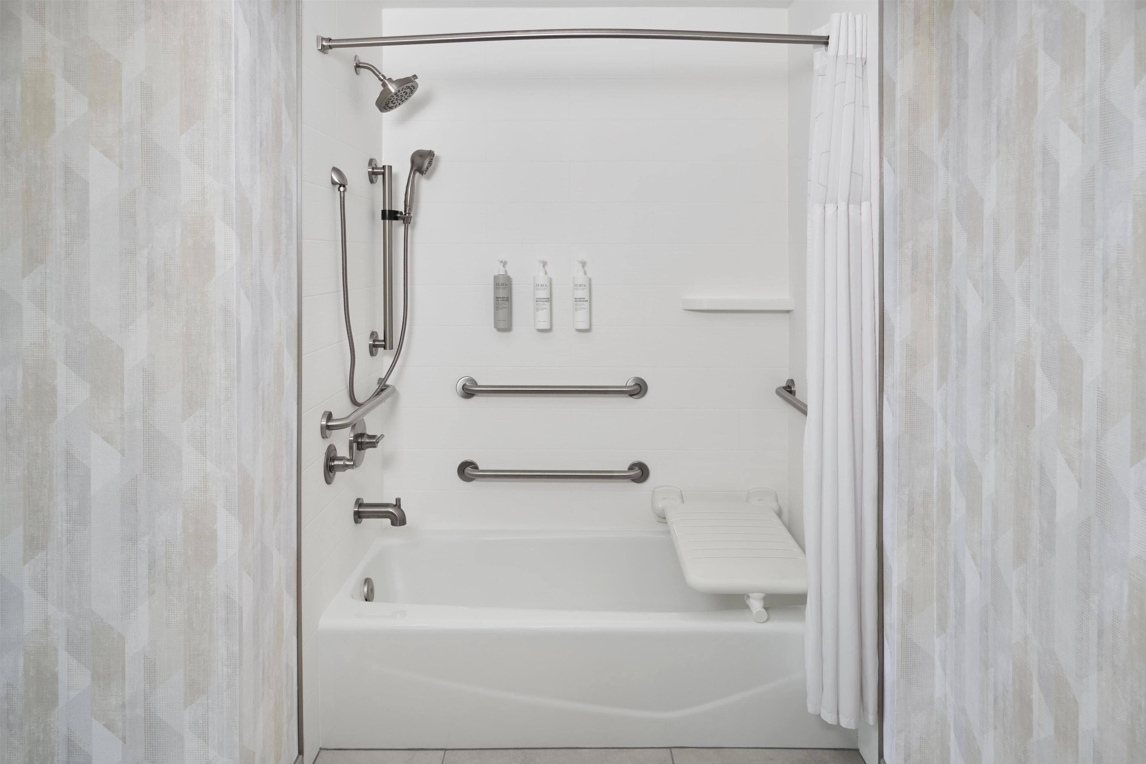 Un baño moderno con bañera, ducha y barras de apoyo.
