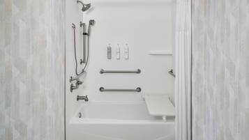 Un baño moderno con bañera, ducha y barras de apoyo.