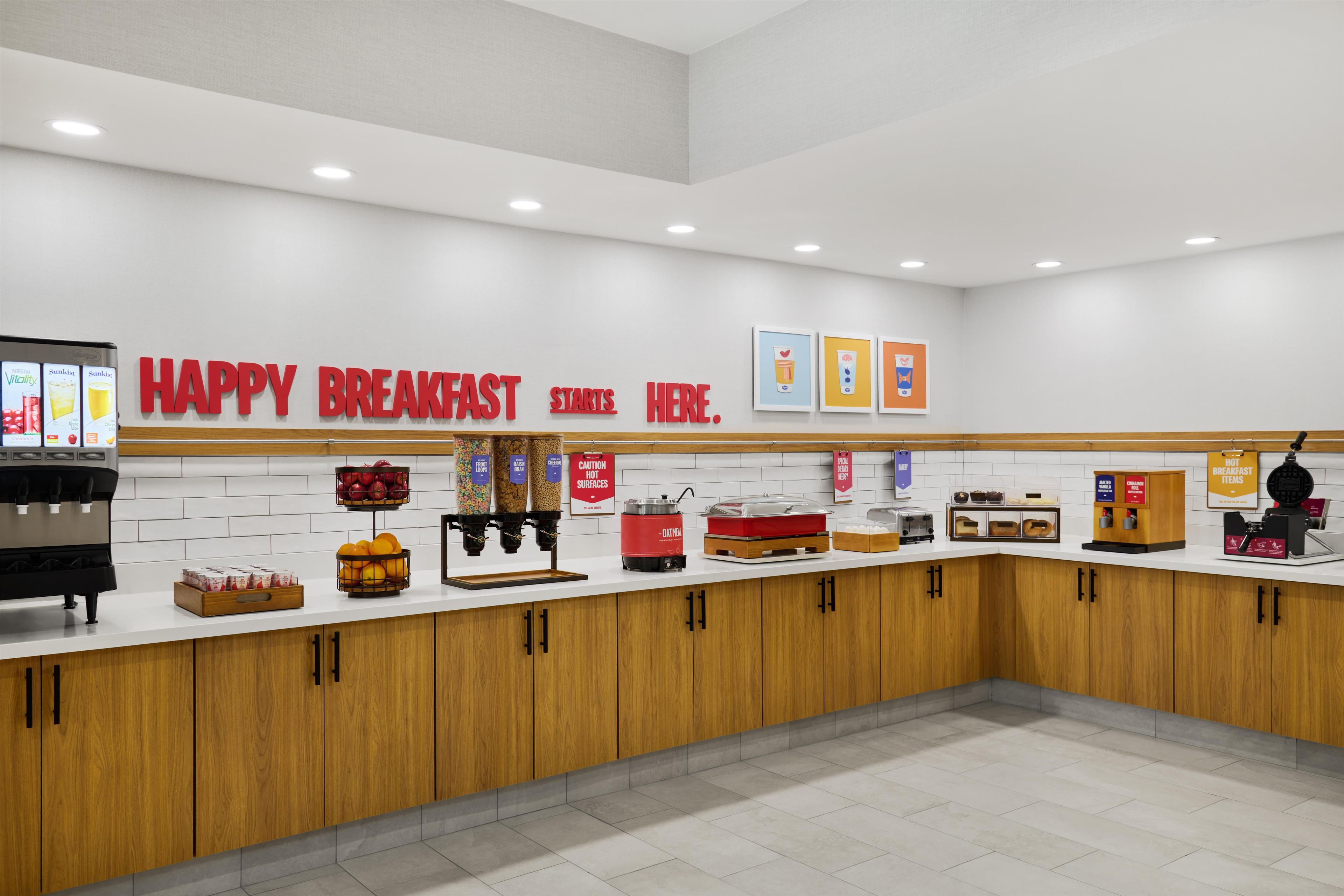A breakfast area with a counter, coffee machines, and a sign that says 'HAPPY BREAKFAST STARTS HERE.'