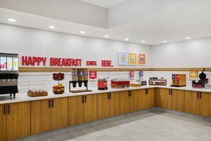 A breakfast area with a counter, coffee machines, and a sign that says 'HAPPY BREAKFAST STARTS HERE.' - Hampton Inn by Hilton Odessa (Odessa)