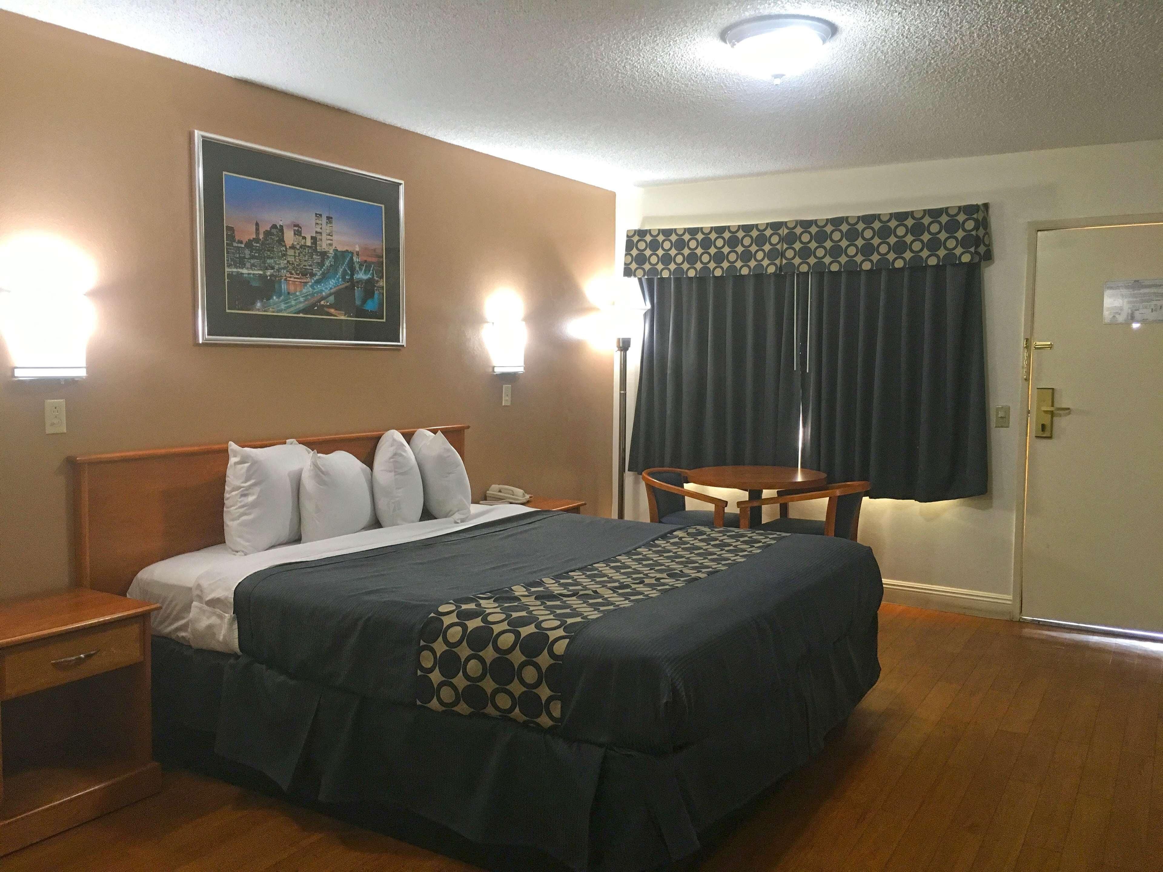 Une chambre d’hôtel avec un lit, une table de chevet, une lampe et un tableau au mur.