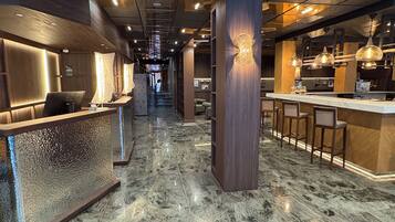 Un vestíbulo de hotel moderno con mostrador de recepción, zona de bar y asientos.
