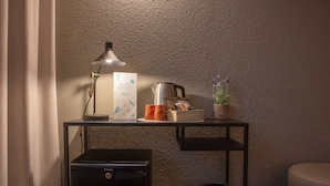 A small desk with a lamp, a coffee pot, a potted plant, and a trash can. - Yomo Eureka (Escaldes-Engordany)