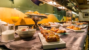 A buffet with various food items, including pastries and a glass of orange juice. - Yomo Eureka (Escaldes-Engordany)
