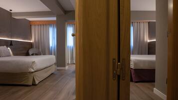 A modern hotel room with a large bed, a smaller bed, and a wooden door.