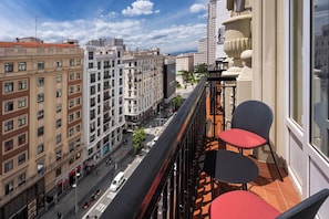 A balcony with two chairs and a table, overlooking a busy street with buildings and a clear sky. - Catalonia Plaza España Hotel & Spa (Madrid)