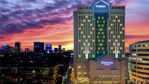 Un edificio de gran altura con el letrero "FORTUNA", rodeado de otros edificios, durante el crepúsculo.