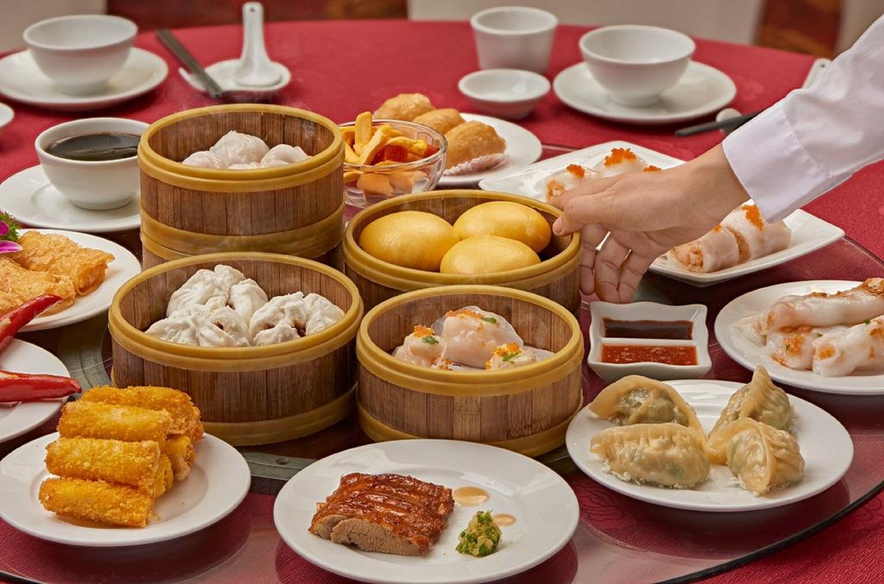 A table with various dishes including dumplings, fried items, and a plate of sliced meat, suggesting a meal setting.