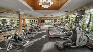 Un gimnasio con varias cintas de correr, bicicletas estáticas y elípticas.