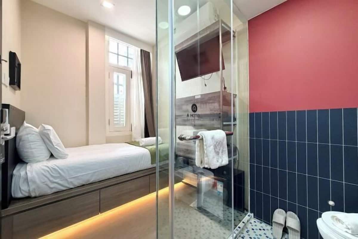 Quarto de hotel com cama, chuveiro e vaso sanitário.