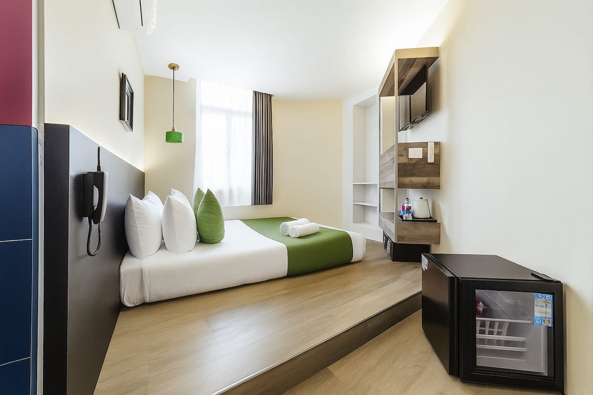 Quarto de hotel moderno com cama, escrivaninha, telefone e minibar.