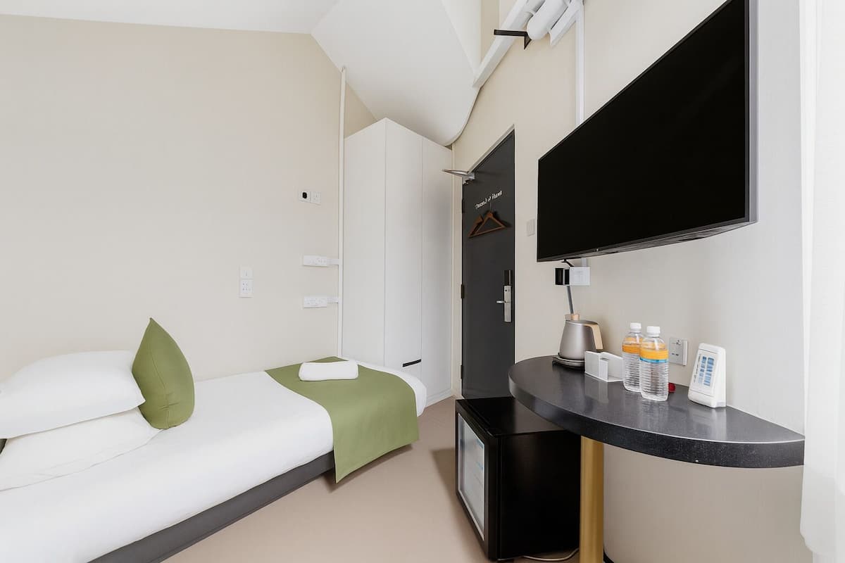 Quarto de hotel com cama, escrivaninha, televisão e minibar.