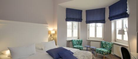 Una habitación de hotel con una cama, dos sillas, un escritorio y un radiador.
