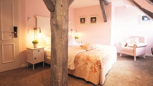 A bedroom with a bed, nightstand, chair, and wooden beams.